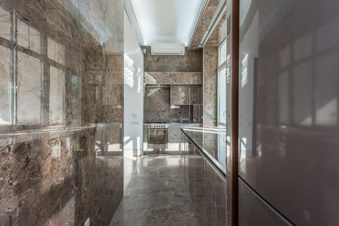 A compact kitchen with marble surfaces, an oven and a bright window