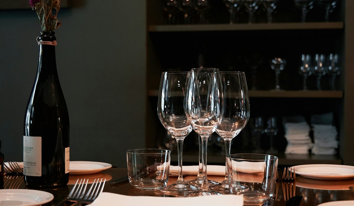 A restaurant table set with plates and wine glasses
